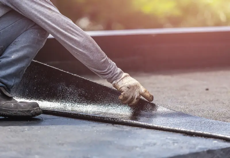 A roofer installs a waterproof barrier on a roof in Alabama or the Florida Panhandle